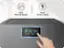 The image features a person's hand pressing a button on a washing machine, which has a 7-inch wide LCD display and touch screen control. The machine is designed for efficient washing and drying, with a super speed feature for quicker processing. The hand is pointing at the control panel, indicating the user's interaction with the device.