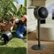The image showcases two different types of fans. The first fan is an outdoor fan, designed to be tough and durable, while the second fan is an indoor fan, sleek and modern. The outdoor fan is placed in a grassy area, while the indoor fan is situated in a living room. The two fans are positioned next to each other, highlighting their contrasting styles and purposes.