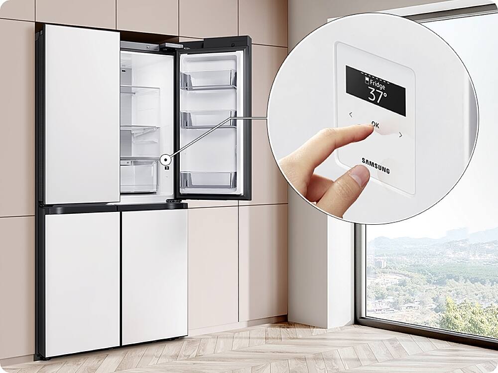 The image shows a kitchen with a refrigerator and a window. The refrigerator is white and has a digital display on the front. A hand is seen pressing a button on the display, possibly adjusting the temperature or selecting a specific setting. The refrigerator is a Samsung model, as indicated by the brand name displayed on the front.