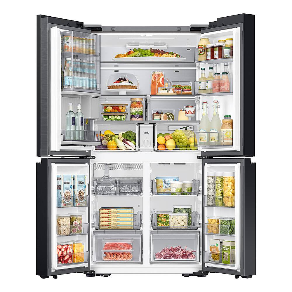 The image features a large, open refrigerator filled with a variety of food items. The refrigerator is stocked with multiple bottles, including water and juice, as well as several fruits such as apples and oranges. There are also multiple sandwiches and a cake inside the fridge. The refrigerator is well-organized and appears to be well-stocked, making it an ideal choice for those who enjoy having a variety of food options at their disposal.