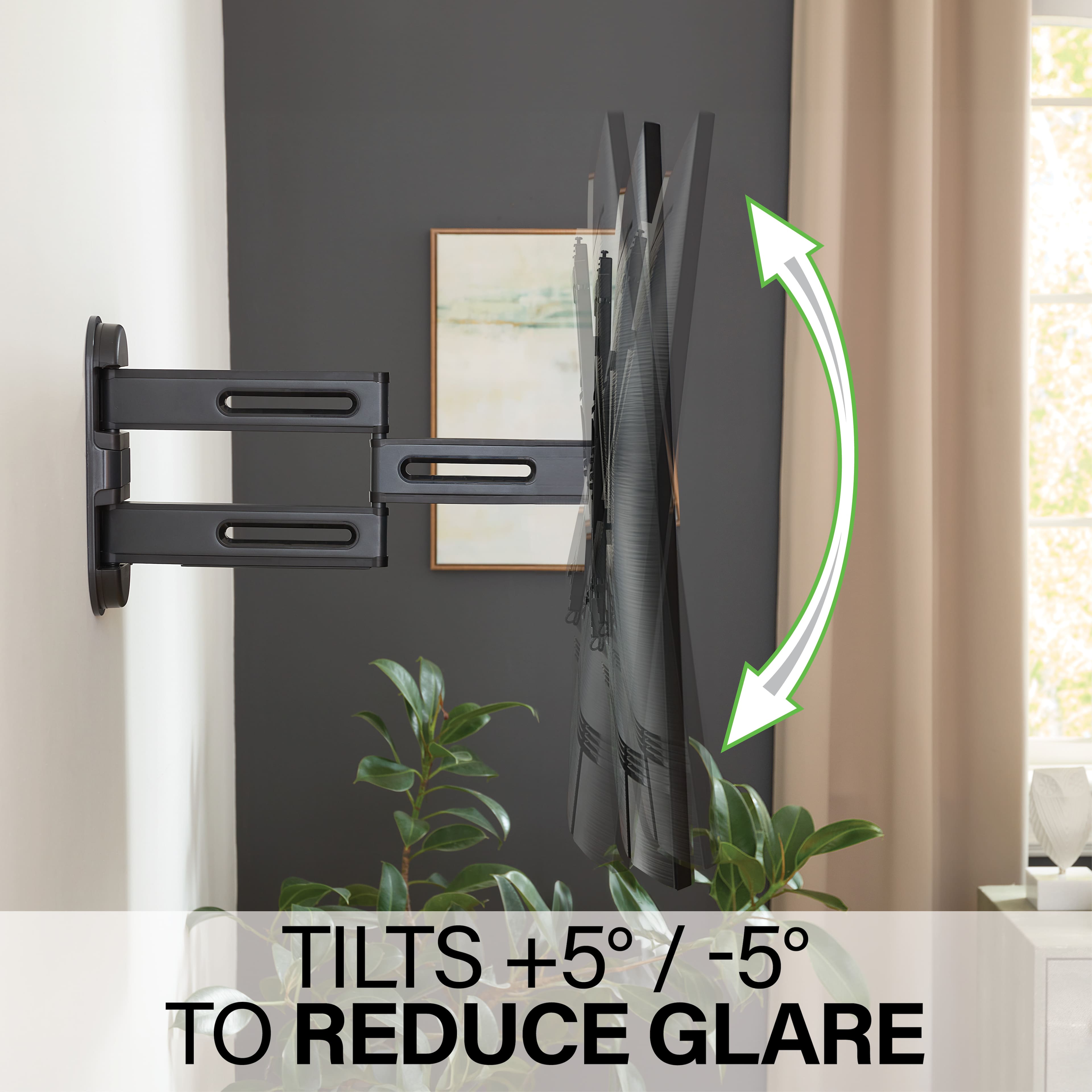 The image shows a room with a large picture hanging on the wall. The picture is positioned at an angle, which is likely to reduce glare. The room also has a potted plant and a vase, adding to the overall decor. The angle of the picture is described as a tilt, which can be adjusted to reduce glare. The tilt is shown with a green arrow pointing upwards, indicating that the picture is currently tilted to reduce glare. The text "TILTS +5/-5 / -5 TO REDUCE GLARE" is displayed at the bottom of the image, emphasizing the purpose of the tilt to reduce glare.