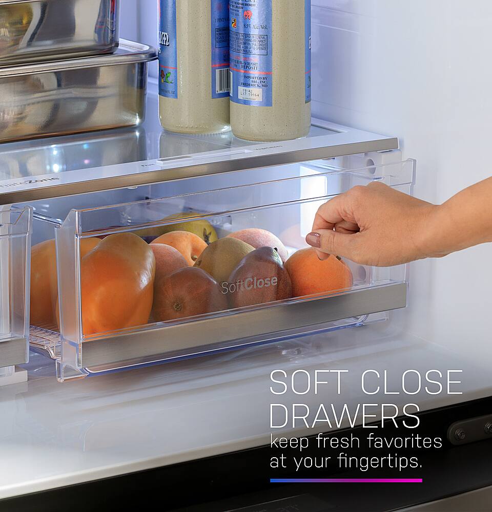 The image features a refrigerator with a person's hand reaching in to grab a piece of fruit, specifically an orange. The refrigerator is filled with various food items, including bottles and other fruits. The hand is grabbing the orange from a drawer, which is a soft close drawer, ensuring that the drawer closes gently and smoothly. The refrigerator is a full-size refrigerator, providing ample storage space for fresh fruits and other items.