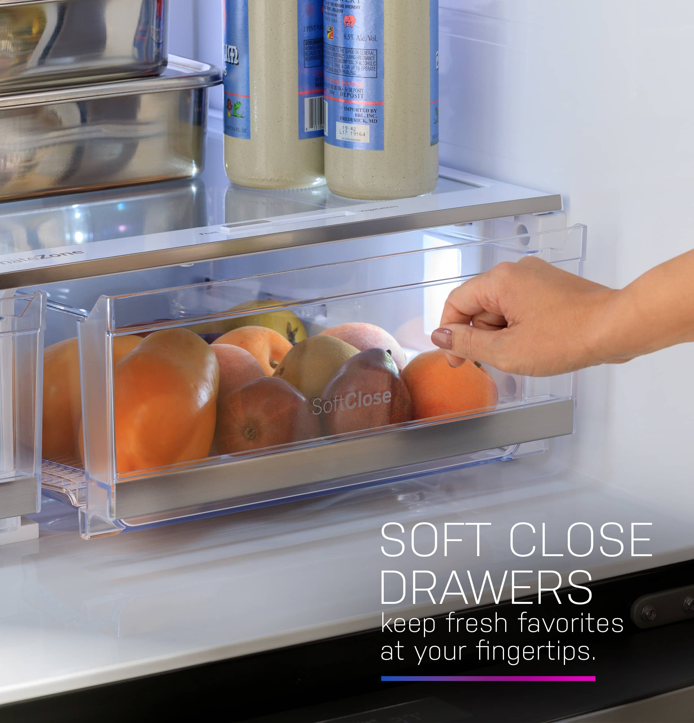 The image features a refrigerator with a person's hand reaching in to grab a piece of fruit, specifically an orange. The refrigerator is filled with various food items, including bottles and other fruits. The hand is grabbing the orange from a drawer, which is a soft close drawer, ensuring that the drawer closes gently and smoothly. The refrigerator is a full-size refrigerator, providing ample storage space for fresh fruits and other items.
