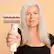 The image features a woman with gray hair holding a hair dryer, which is a product from the brand RapidGloss. The hair dryer is designed to minimize frizz and provide a smooth finish, as indicated by the "Styles Finisher without the frizz" slogan. The product is based on Coanda Technology, which ensures air-drying efficiency. The image also includes a tagline that says "1H RapidGloss Styles Finisher without the frizz with Coanda Technology."