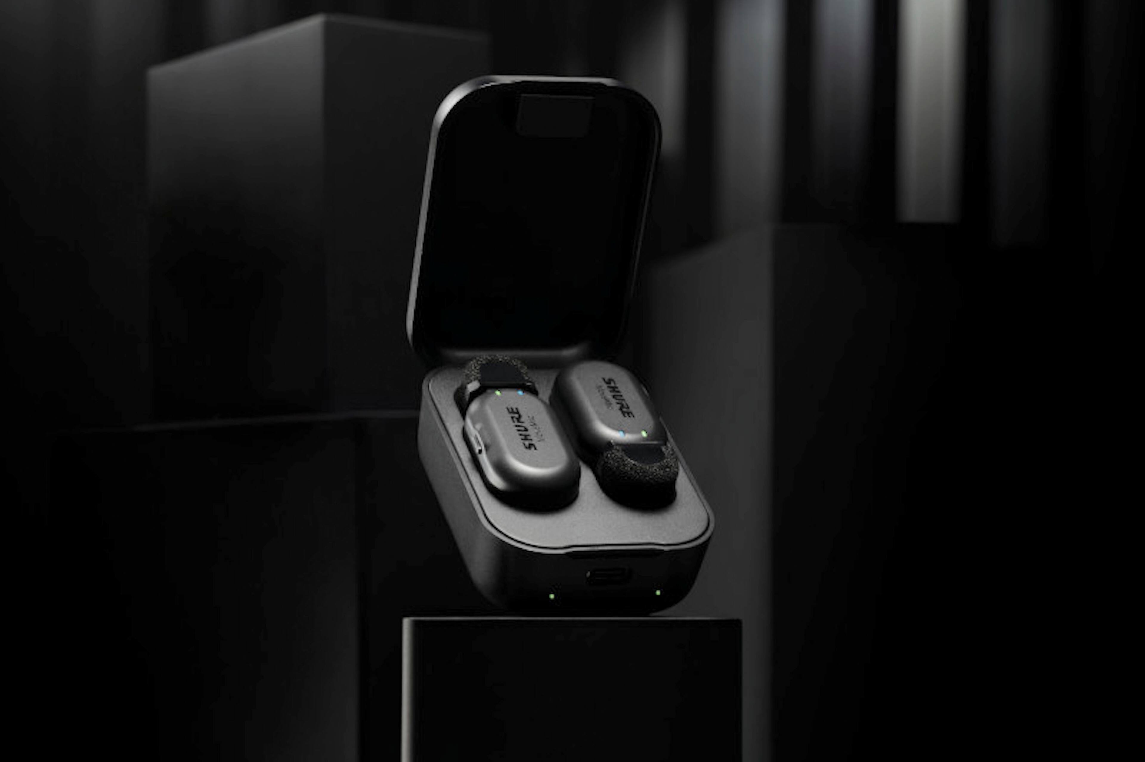 The image features a cell phone with a Mission Control app on the screen, which allows for direct-to-phone recording. The phone is placed on a table, and there are two earphones nearby. The ShurePlus MOTIV app enables users to access various features, such as speech mode, mute, and presets, to enhance their recording experience.