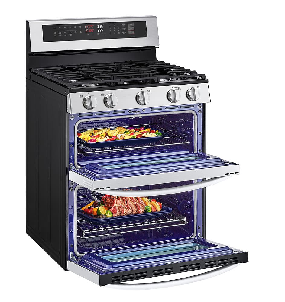 The image features a stainless steel oven with two trays of food inside. The oven has a blue interior, and there are multiple vegetables and meat items being cooked. The oven is open, revealing the delicious meal being prepared. The oven has a large capacity, as it can accommodate multiple trays of food at once.