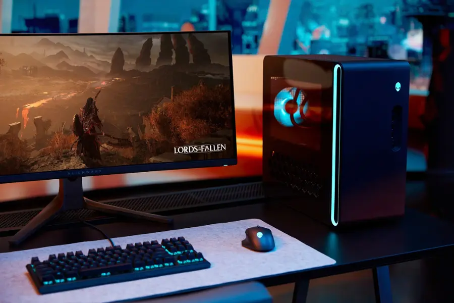 The image features a desktop computer setup with a monitor, keyboard, and mouse. The monitor displays the game "Lords of the Fallen," while the Alienware computer tower is situated next to the monitor. The keyboard and mouse are placed on a desk, ready for use. The scene is set in a dark room, creating a focused and immersive gaming environment.