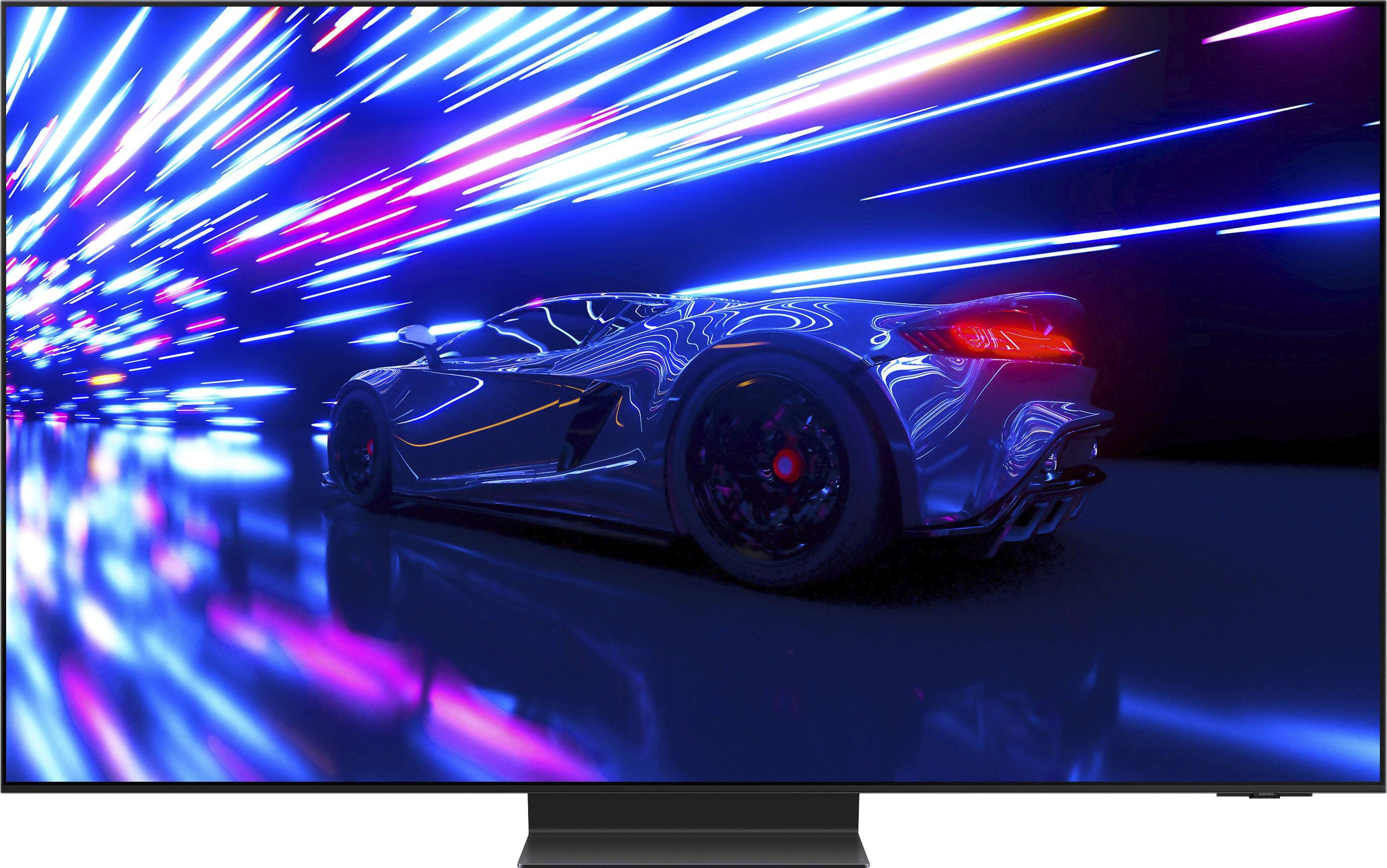 The image features a large Samsung television, which is a 55" S95D OLED model. The TV is placed on a stand, and the dimensions of the TV without the stand are 48.2 x 27.8 x 0.4 inches. The TV with the stand is 48.2 x 30.4 x 10.5 inches. The television is accompanied by a remote control, a power cable, and a slim cable. The TV also comes with a user manual and a solar cell remote. The image provides a clear view of the television and its dimensions, making it an informative visual for potential buyers.
