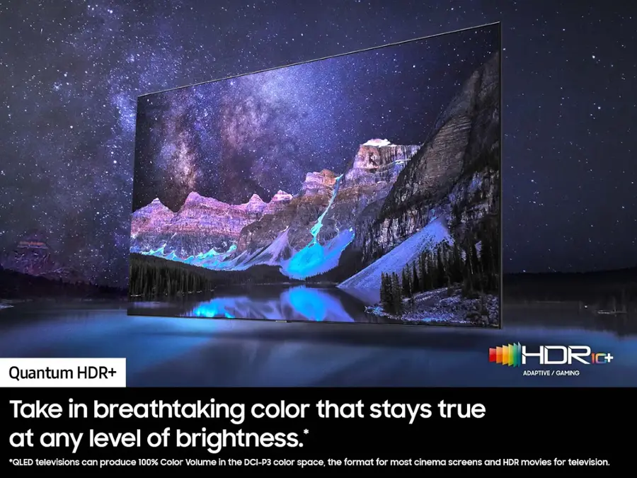 The image features a large screen television with a stunning mountain scene displayed on it. The television is advertised as having Quantum HDR+ Adaptive technology, which allows for breathtaking color that stays true at any level of brightness. The advertisement emphasizes the television's ability to produce 100% Color Volume in the DCI-P3 color space, making it ideal for watching HDR movies and gaming.
