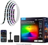 The image features a Govee Smart TV Backlight 3S box with a colorful rainbow light on the front. The box is placed next to a cell phone, and there is also a remote control nearby. The backlight is designed to enhance the movie-watching atmosphere with just one tap, and it comes with various modes, including music mode, color cycle, and camera mode. The Govee works with both Alexa and Google Home, making it a versatile and convenient addition to any living space.