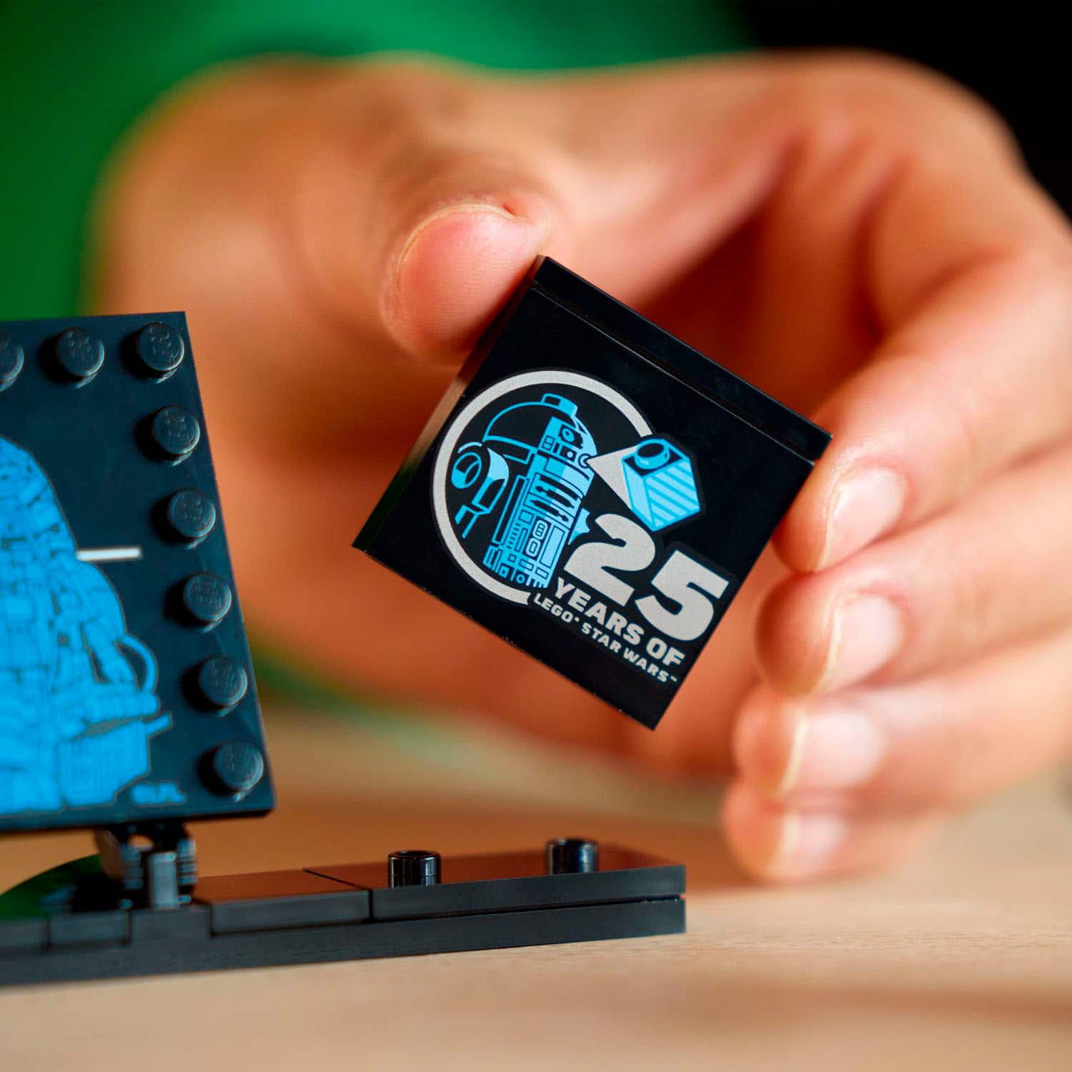 The image shows a person holding a small Lego piece, which is a celebration of 25 years of Star Wars. The person is holding the Lego piece in their hand, showcasing the tiny size of the commemorative piece.