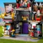 The image shows a Lego house with a purple door and a yellow roof. The house is filled with various Lego figures, including a family of four, a baby, and a dog. The family members are positioned in different areas of the house, with one figure sitting on a chair, another standing near the door, and the third figure located in the middle of the house. The dog is situated near the right side of the house. The scene captures the essence of a typical Lego playtime, where the figures are arranged in a way that resembles a real-life family living in a house.