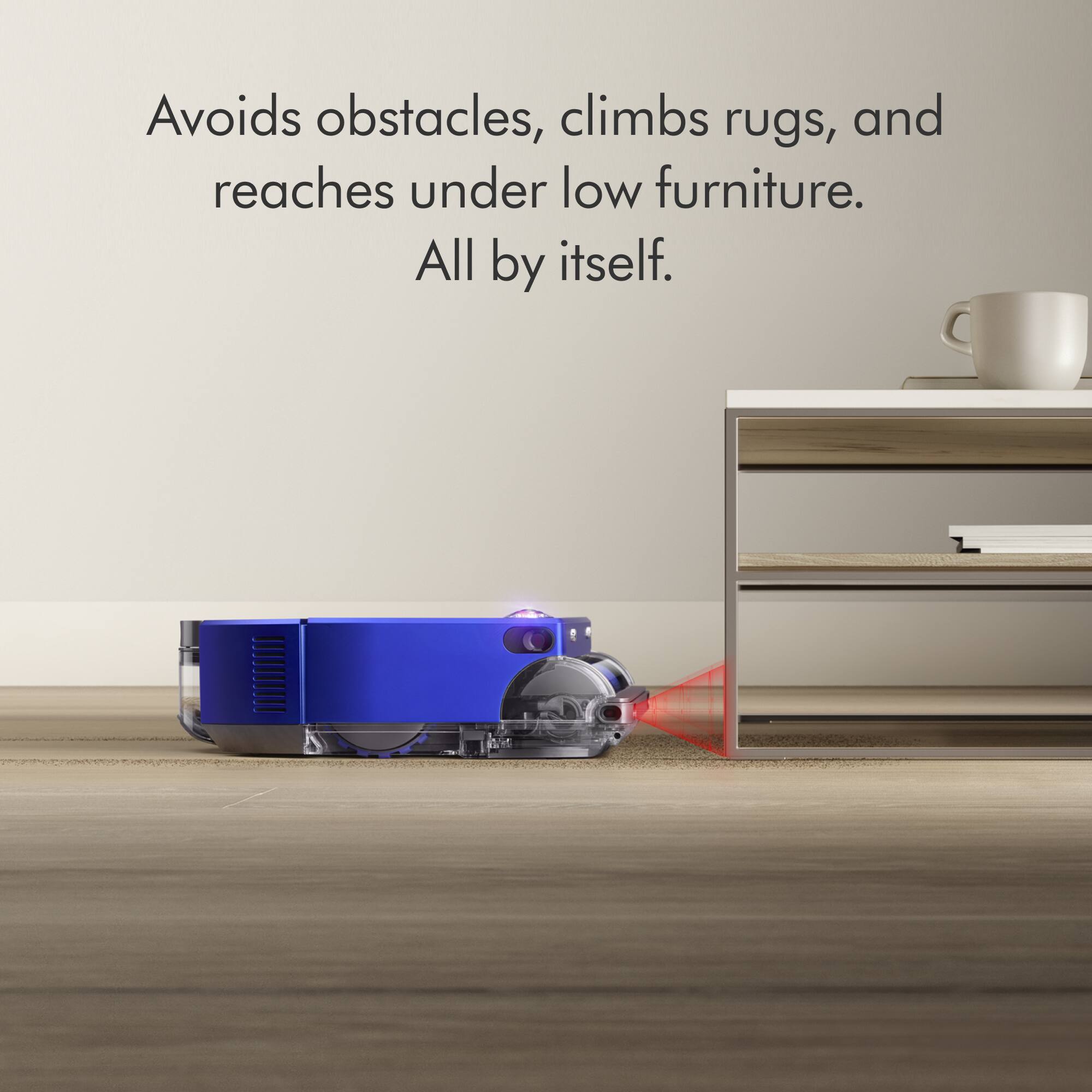 The image shows a blue robotic vacuum cleaner on a wooden floor, with a coffee table and a cup nearby. The vacuum cleaner is designed to avoid obstacles, climb rugs, and reach under low furniture, making it a convenient and efficient cleaning tool.