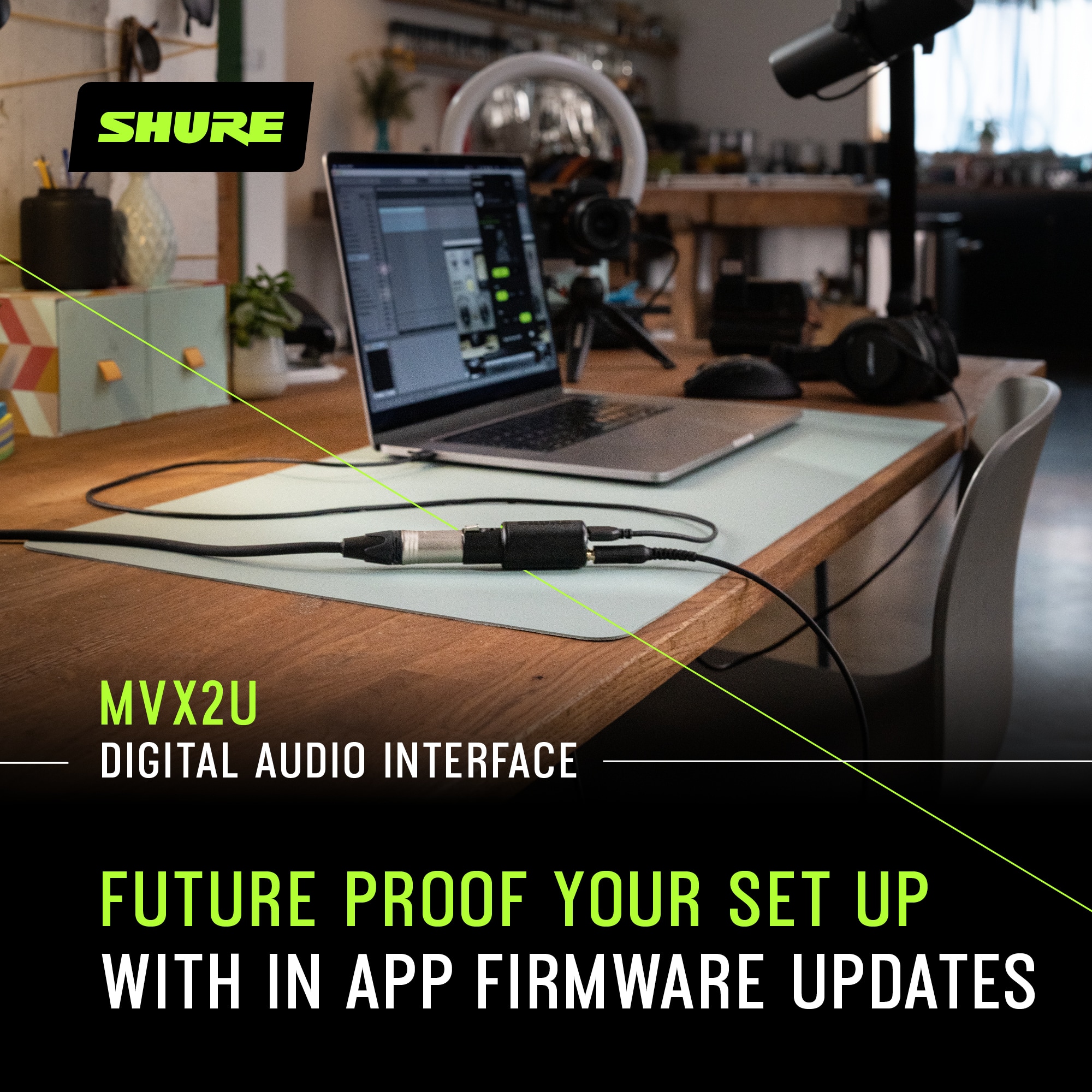 The image features a laptop sitting on a wooden desk, accompanied by a mouse and a cell phone. The laptop is connected to a digital audio interface, which is placed on the desk as well. The scene appears to be a workspace or a home office setup. The advertisement suggests that the Shure MVX2U digital audio interface is future-proof, ensuring that the user's setup remains up-to-date with in-app firmware updates.