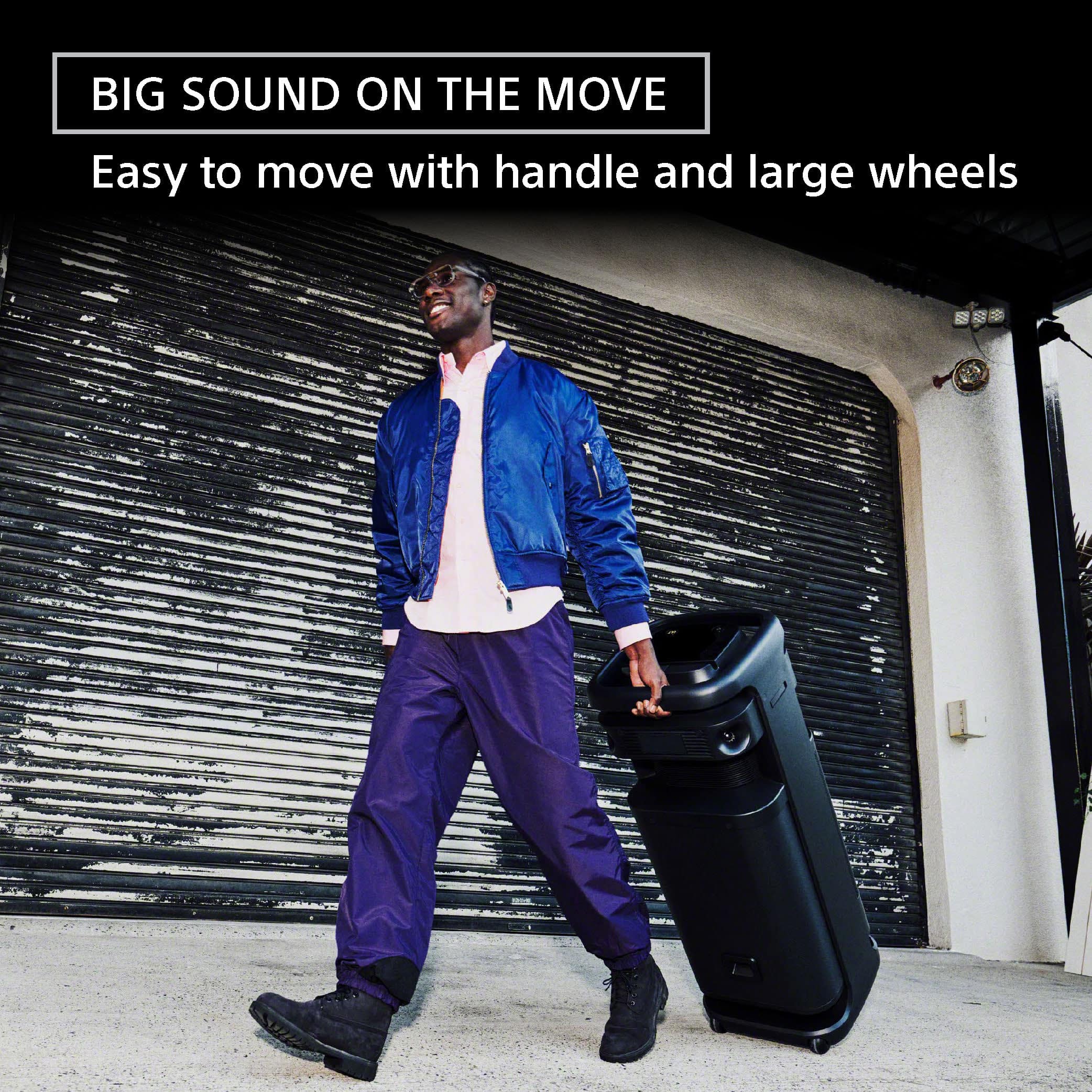 The man in the image is walking with a suitcase and a handbag, both of which have large wheels, making it easy for him to move with them. The suitcase and handbag are designed for easy transportation, with the handle and large wheels providing convenience and mobility.