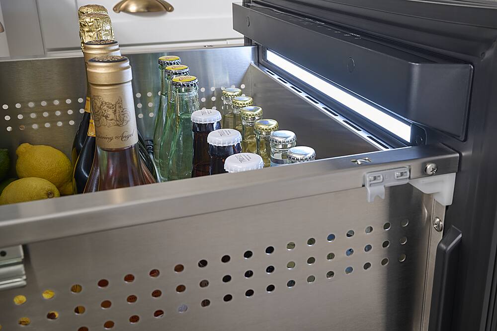 The image shows a refrigerator with a drawer full of beer and wine bottles. There are a total of 12 bottles, including both beer and wine, neatly arranged in the drawer. The refrigerator also has a light on, illuminating the bottles and making them easily visible. The variety of bottles suggests that the refrigerator is well-stocked for entertaining guests or enjoying a selection of beverages at home.