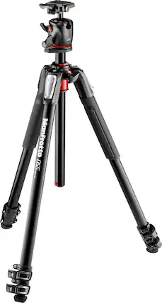 The image features a Manfrotto tripod with a black and red color scheme. The tripod has three legs and a camera mount on top, making it suitable for photography and videography purposes. The legs are spread apart, providing stability for the camera setup.