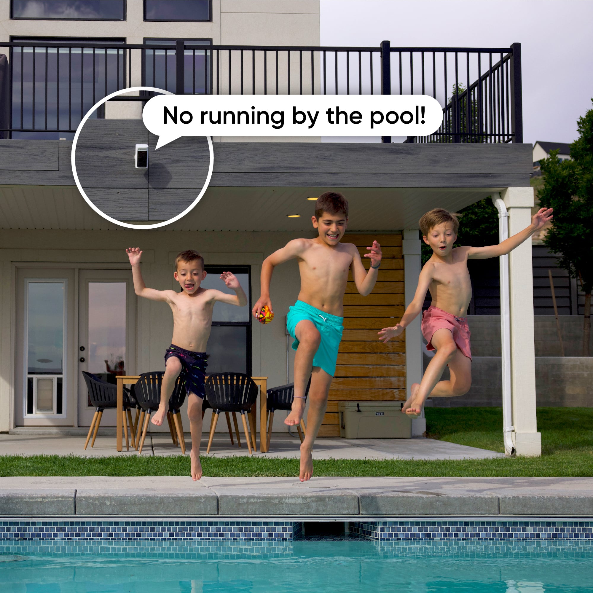 The image shows three young boys jumping into a swimming pool. The largest text in the image reads, "No running by the pool!" This suggests that the children are engaging in playful behavior and are not following the rules of the pool area. The image is categorized as Surveillance_Cameras, which implies that the pool area is being monitored for safety and compliance with pool rules.