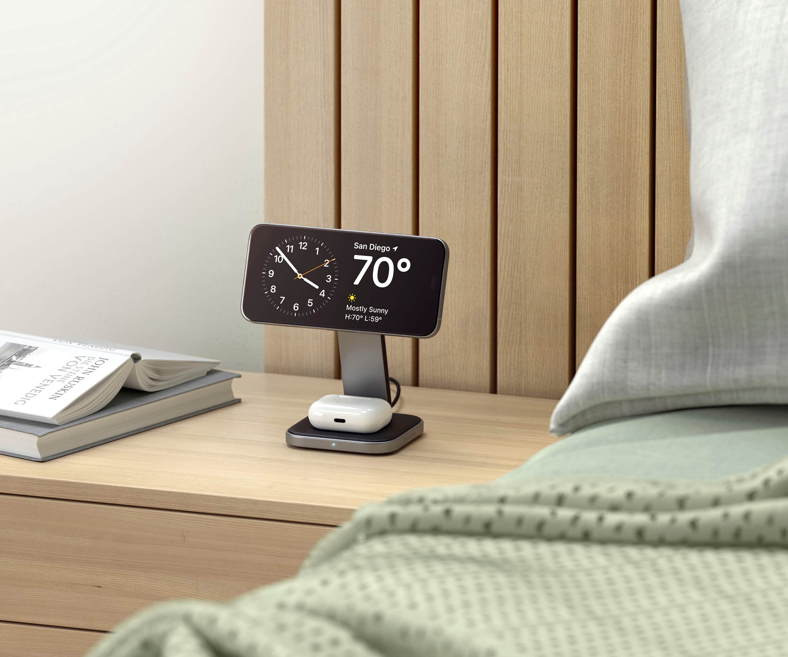 The image shows a bedroom with a bed and a nightstand. On the nightstand, there is a digital clock displaying the time as 7:00. The clock is placed on a wooden surface, and the bed is positioned nearby. The room appears to be well-organized and comfortable.