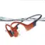 The image features a pair of waterproof headphones, with one earpiece submerged in water. The headphones have a bright orange and blue color scheme, and they are designed to be used while swimming or engaging in water-based activities. The headphones are equipped with a built-in microphone and a control button, making them suitable for listening to music, podcasts, or making calls while in the water.