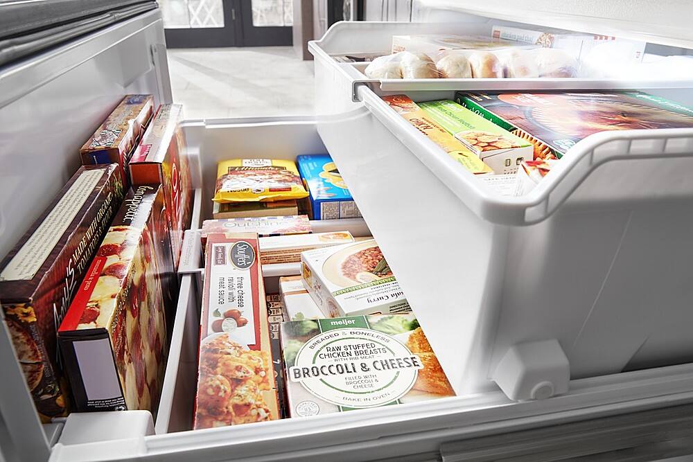 The image shows a refrigerator with its door open, revealing a variety of food items inside. There are several boxes of pizza, some of which are placed in the middle and bottom sections of the refrigerator. Additionally, there are multiple bottles of beer, with some located in the upper right corner and others scattered throughout the refrigerator. The refrigerator is filled with a diverse assortment of food and drinks, making it a well-stocked and convenient place for meal preparation and consumption.