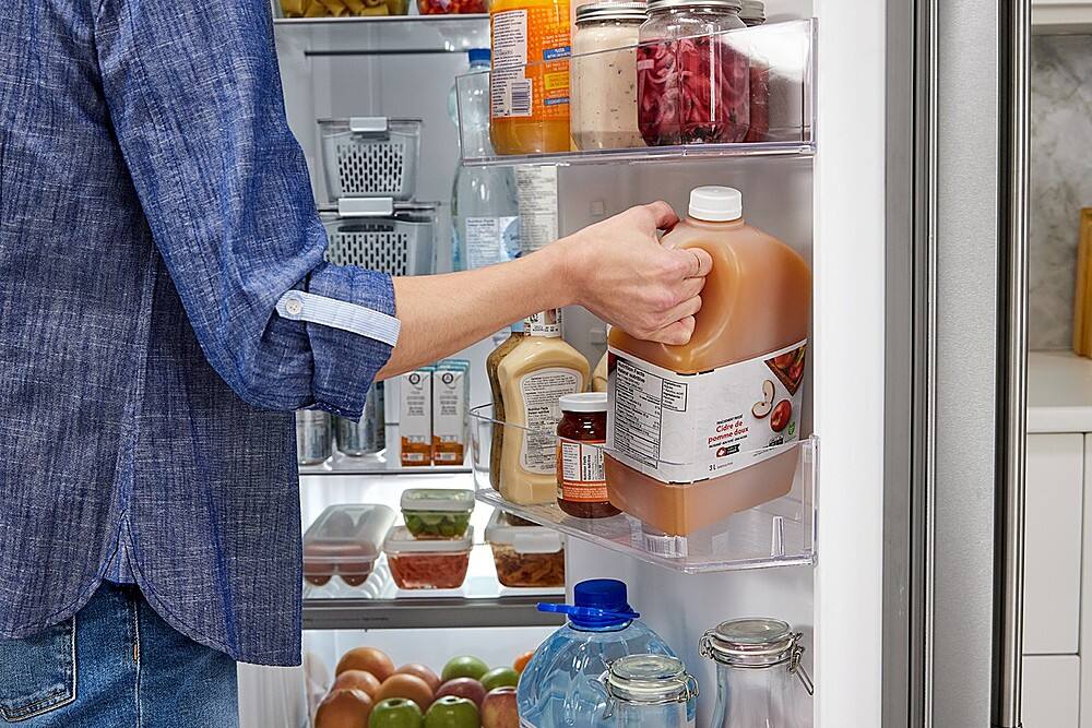The text on the image reads "3 CILLE by - de Cidre doux pomme LE." However, this text is not in English and appears to be in a different language. The image shows a person holding a bottle of apple cider from the refrigerator.