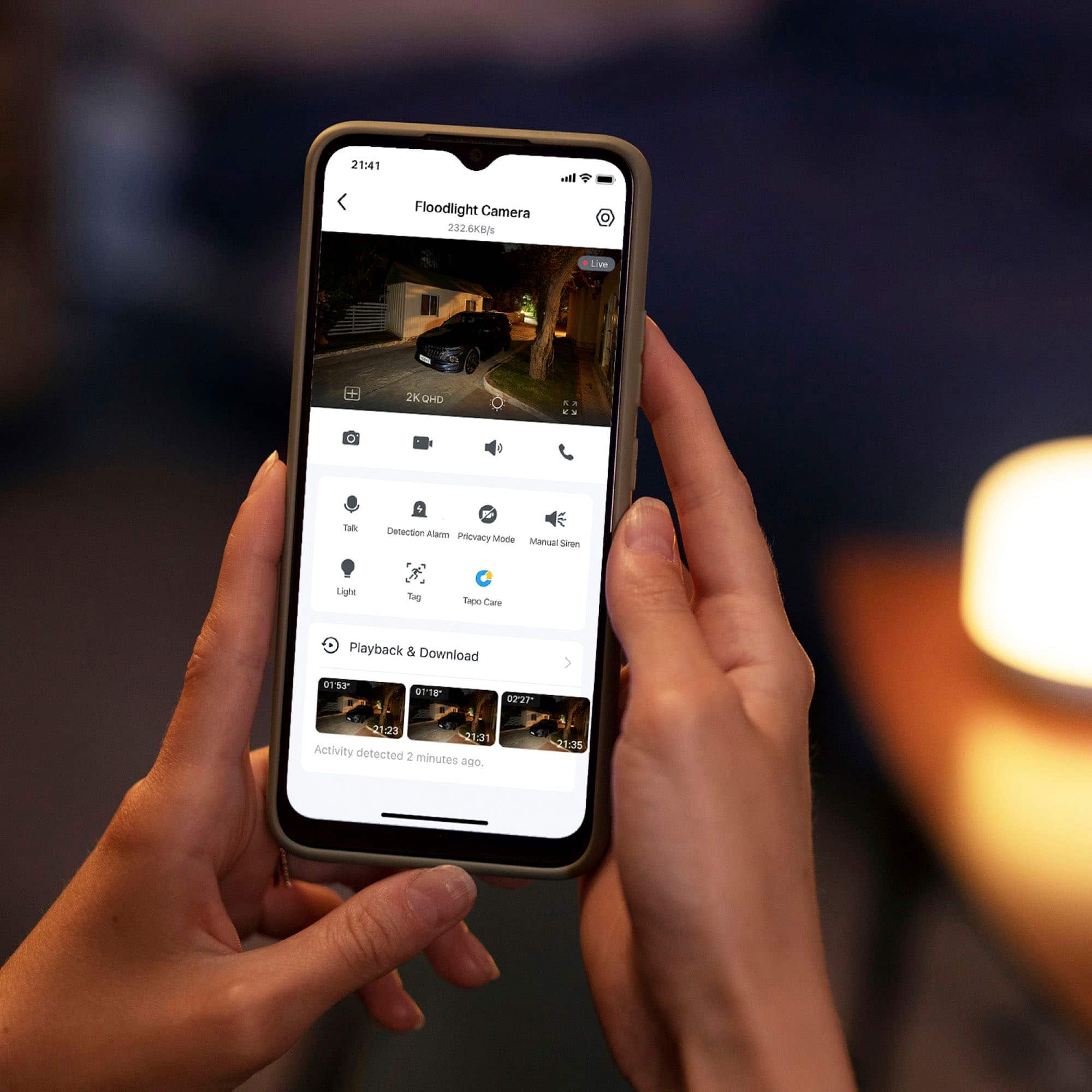 The text on the image reads: "21:41 lo Floodlight Camera 232.6KBN Live 2KGHD a .. . Talk R E Detection Alarm Privacy Mode Manual Siren Light Tag Tapo Care Playback & Download 0153 0TT8 02:27 21:23 2:31 Activity detected 2 minutes ago."