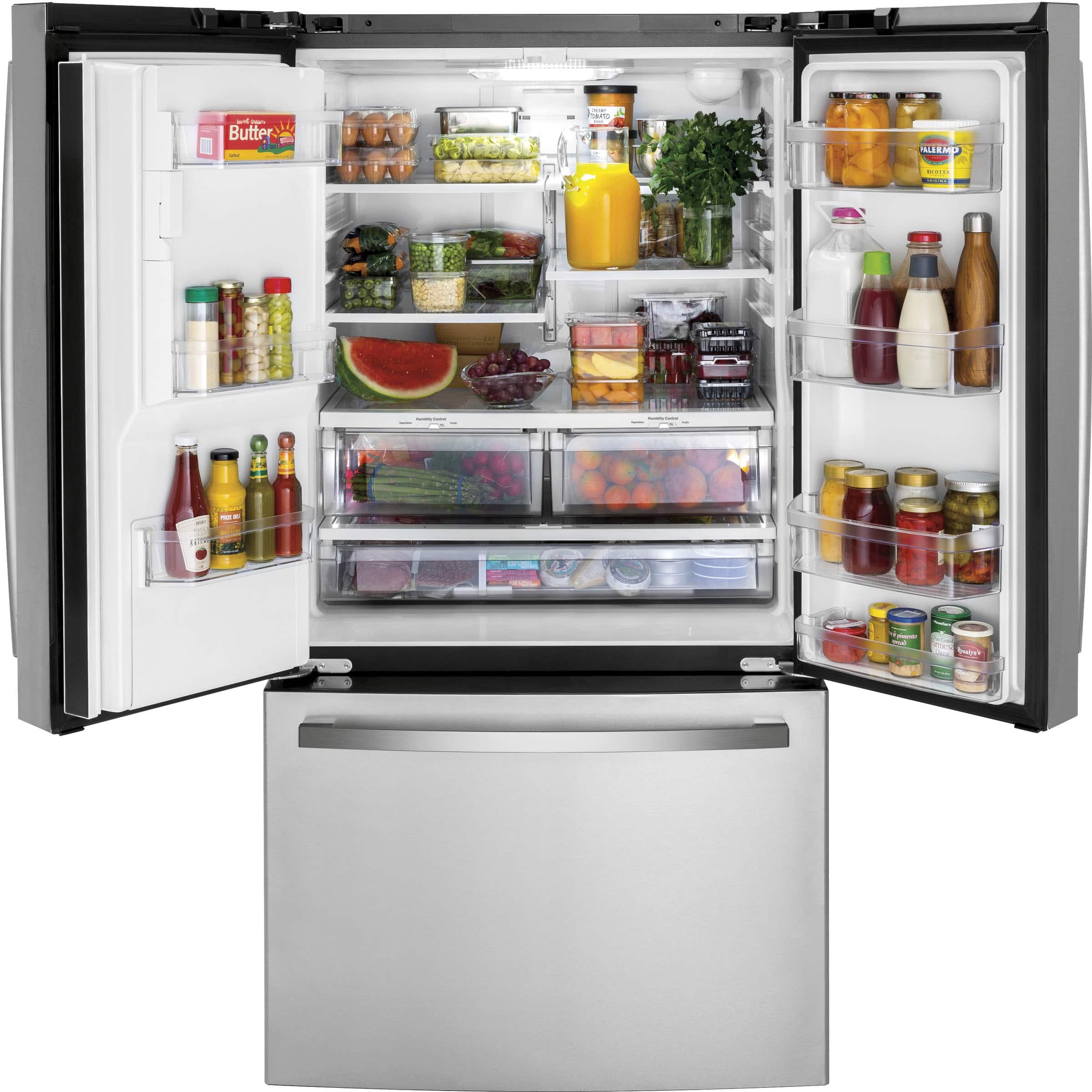 The image features a large refrigerator filled with various food items and drinks. The refrigerator is stocked with a variety of bottles, including juices and other beverages. There are also several bowls containing fruits and vegetables, such as apples and oranges. The refrigerator is well-organized, and the items are easily accessible. The refrigerator is likely used to store fresh produce, beverages, and other food items for a family or household.