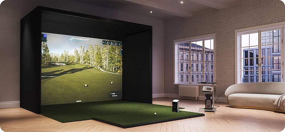 The image features a large screen TV in a room with a golf course displayed on it. The TV is placed in front of a window, which allows natural light to enter the room. There is a couch in the room, and a remote control can be seen nearby. The room appears to be a living room or a recreational space where people can enjoy watching golf or other sports on the big screen.