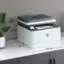 The text on the image reads: "12.3" H 5 A hp  NP n0  Eaerat 15.7" D 16.5" W." This text is describing the dimensions of a printer, specifically the height, width, and depth. The printer is 12.3 inches high, 5 inches wide, and 15.7 inches deep.