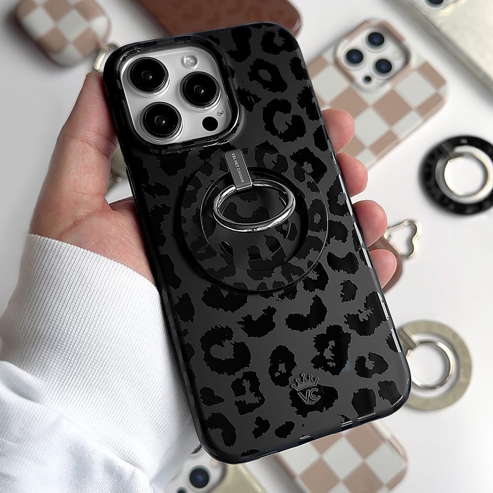 The image features a person holding a black and white cell phone case with a leopard print design. The case is being held in front of a white background, which also has a checkered pattern. The person's hand is prominently visible in the foreground, while the cell phone case is the main focus of the image.