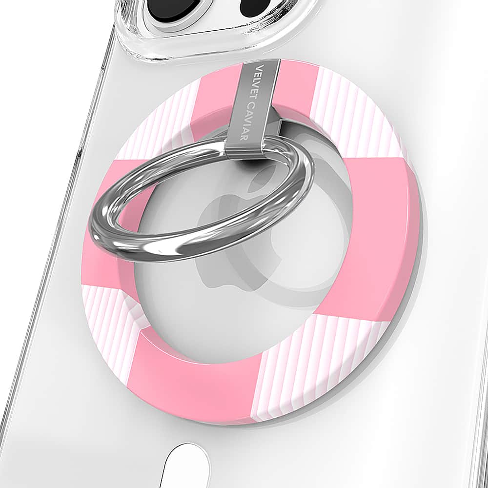 The image features a white cell phone with a pink and white case on it. The case has a ring attached to it, which is likely used for attaching the phone to a wrist or other objects. The case is designed by Velvet Caviar, and it adds a touch of style and personalization to the phone.