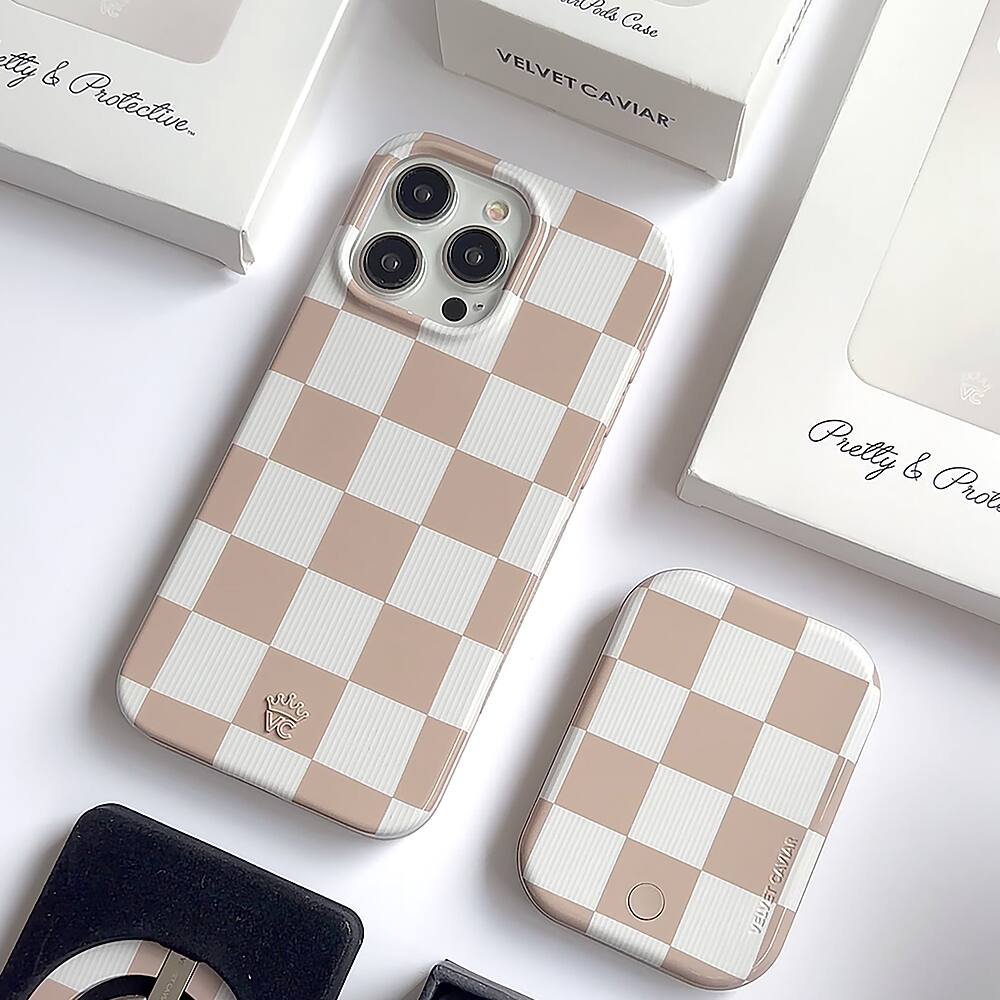 The image features a white and pink checkered case for a cell phone, along with a smaller case. The case is designed by Velvet Caviar and is made of leather. The image also includes a box with the word "Pretly" on it.