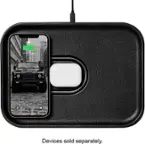 The image features a black case with a white lightning bolt on it, which is charging an iPhone. The case is connected to the iPhone via a cable, and the iPhone is placed inside the case. The case is designed to charge the iPhone while also protecting it from potential damage. The image also shows a car in the background, but it is not the main focus of the scene.