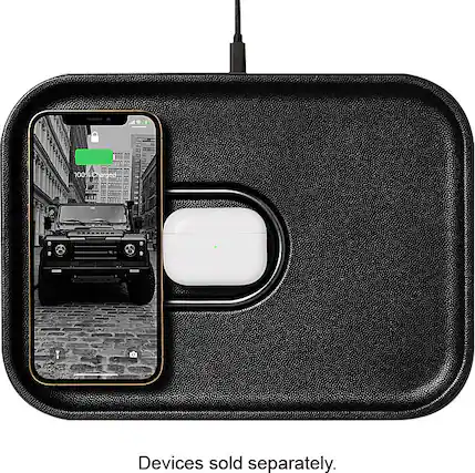 The image features a black case with a white lightning bolt on it, which is charging an iPhone. The case is connected to the iPhone via a cable, and the iPhone is placed inside the case. The case is designed to charge the iPhone while also protecting it from potential damage. The image also shows a car in the background, but it is not the main focus of the scene.