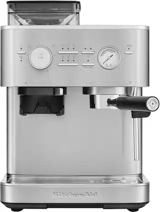 The image features a silver KitchenAid coffee maker with a black handle. The coffee maker has a silver and black color scheme and is designed to make coffee. The coffee maker is sitting on a countertop, and it is ready to be used.
