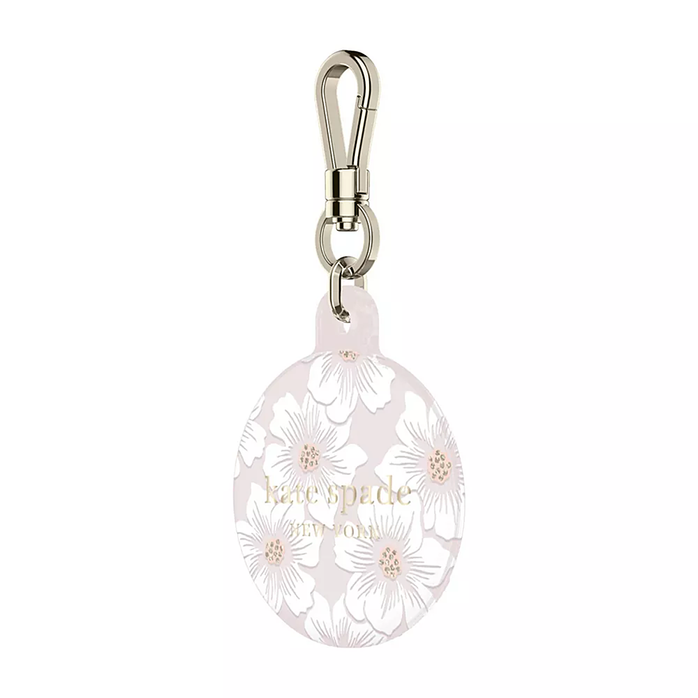 The image features a small, round, white and pink floral-patterned case with a metal chain attached. The case is designed by Kate Spade New York and is likely used for holding a cell phone or other small items. The case is displayed against a white background, which highlights its colorful design and makes it stand out.