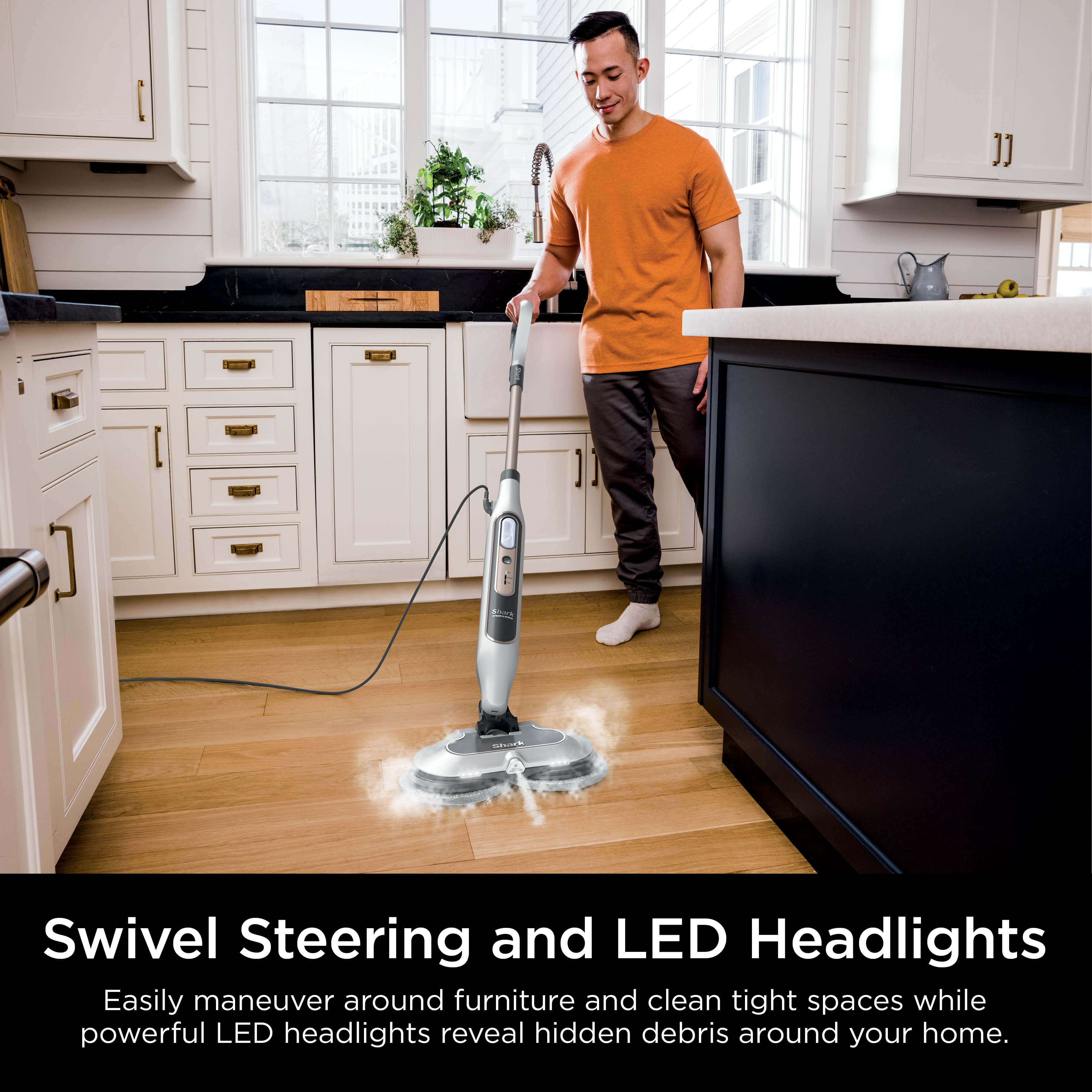 The image features a man in an orange shirt using a Swivel Steering and LED Headlights mop to clean a hardwood floor in a kitchen. The mop has a long handle and a headlight, which allows the man to easily navigate around furniture and clean tight spaces while illuminating hidden debris. The kitchen is equipped with a sink, a refrigerator, and a potted plant, creating a cozy and functional environment for cooking and cleaning.