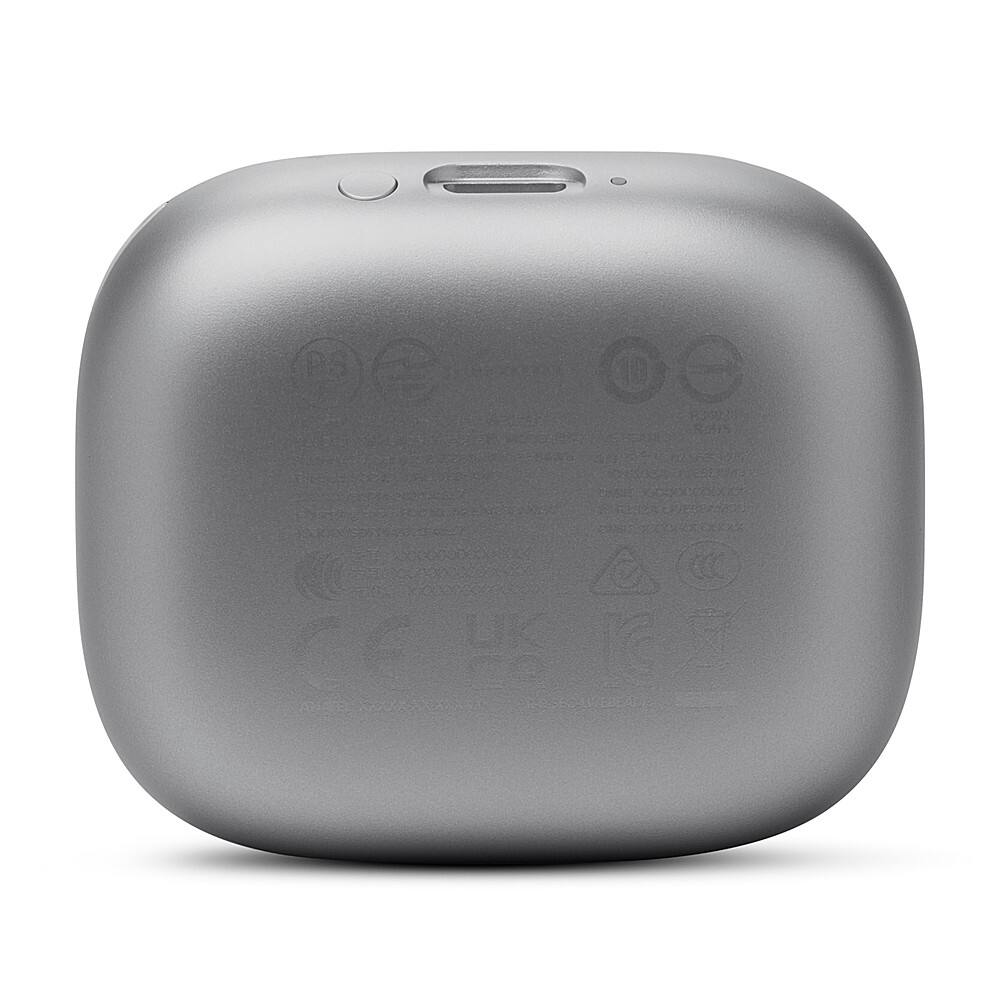 The image features a small electronic device, possibly an iPod, with a grey case. The device has a USB port and a headphone jack on the top. The back of the device displays a warning label, and the bottom of the device has a manufacturer's logo. The device is sitting on a white background, making it the main focus of the image.