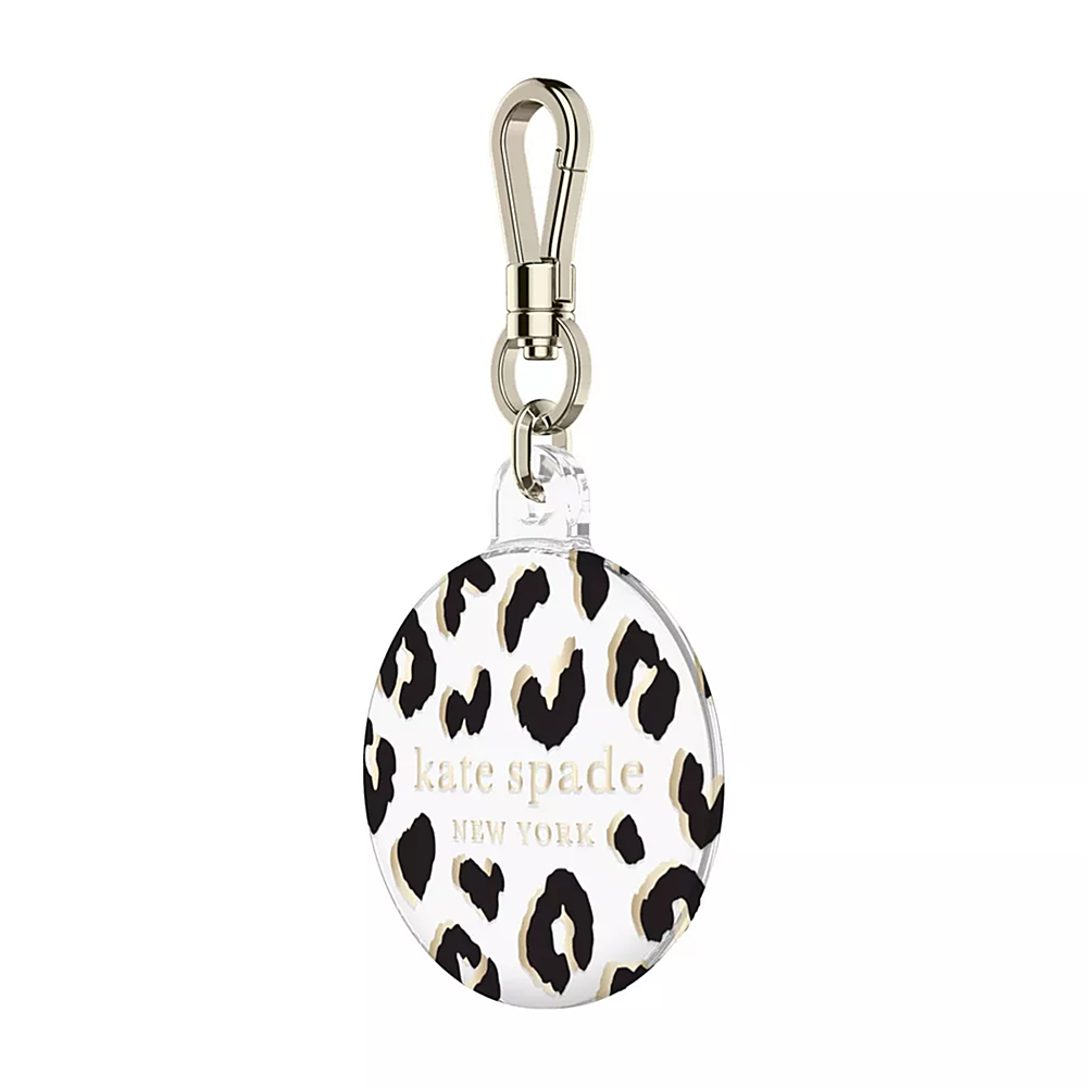 The image features a small, round Kate Spade New York keychain. The keychain is black and white, with a leopard print design. It is attached to a metal ring, making it easy to attach to a bag or keychain. The keychain is a stylish accessory for anyone who loves Kate Spade New York's fashionable designs.