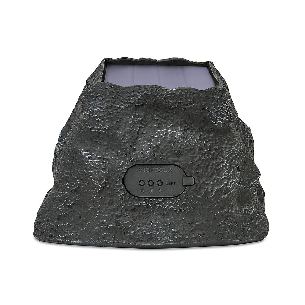 The image features a speaker that is shaped like a rock and has a USB port. The speaker is made by Victrola and is designed to look like a boulder. The speaker is black and has a USB port on the back, making it a unique and interesting addition to any room.
