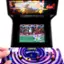 The image features a video game machine with a purple and black color scheme, showcasing a game called "Teenage Mutant Ninja Turtles in Time." The game is displayed on a screen, and a person's hand is visible near the bottom of the image, likely interacting with the game controls. The machine is designed to accept coins, and the game is likely a popular choice among players.