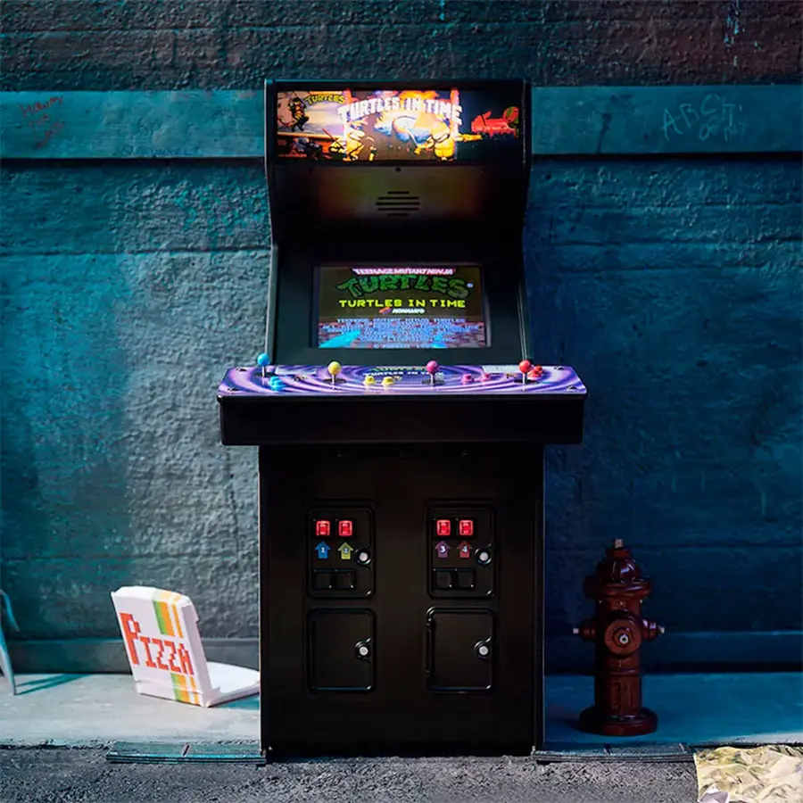 The image features a black arcade machine with a game called "Teenage Mutant Ninja Turtles in Time." The machine is placed on a sidewalk next to a fire hydrant. The machine has a pizza box and a chair nearby, adding to the urban setting.