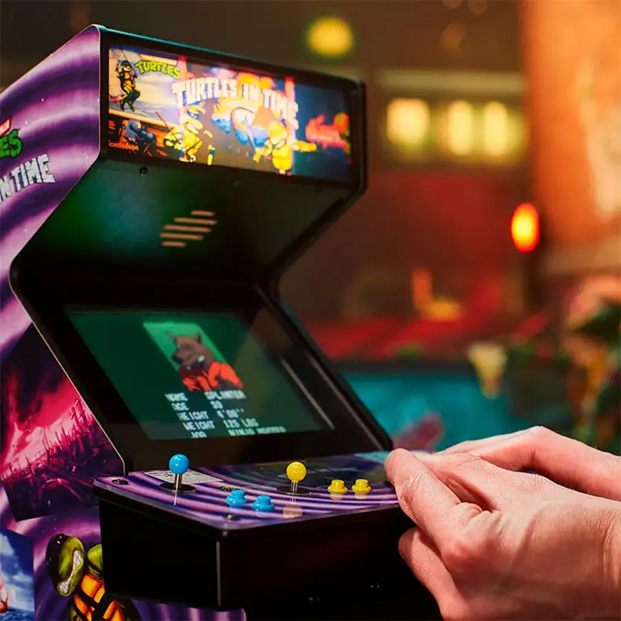 The image features a person playing a video game on a Turtles in Time arcade machine. The machine has a purple and black color scheme, and the game is displayed on a screen. The person is holding a joystick, which is used to control the game. The game is set in a dark room, creating a more immersive gaming experience.