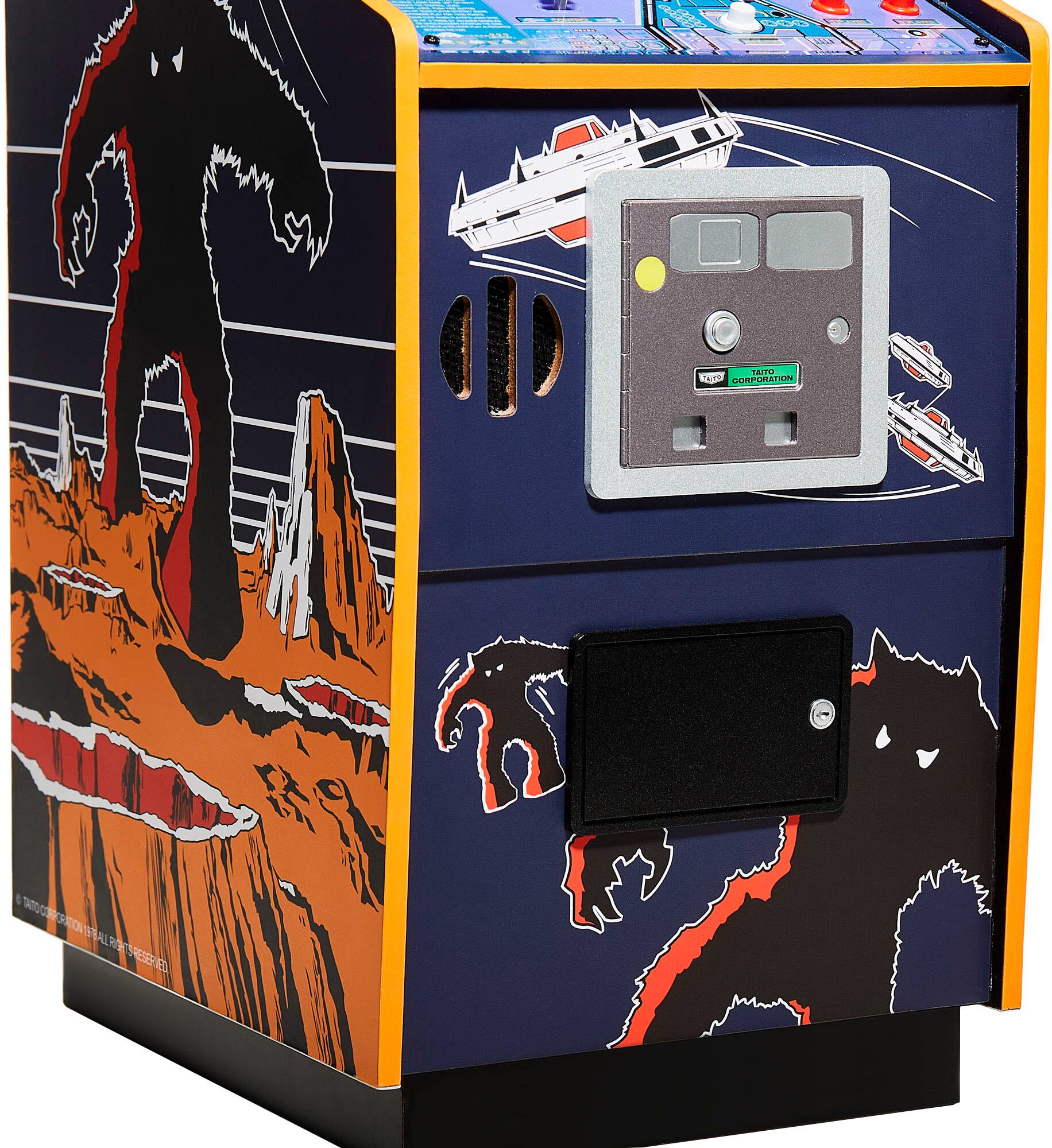 The image features a blue arcade machine with a monster on the front and a spaceship on the top. The machine has a coin slot and a button to start the game. The monster is depicted on the front of the machine, while the spaceship is displayed on the top. The machine is designed to attract players and provide an engaging gaming experience.