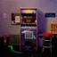 The image features a Space Invaders arcade machine, which is a classic video game. The machine is placed on a carpeted floor, and there is a red stool nearby. The machine is surrounded by a few other objects, including a fire extinguisher, a trash can, and a poster. The scene appears to be set in a casual, informal environment, possibly in a basement or a similar space.