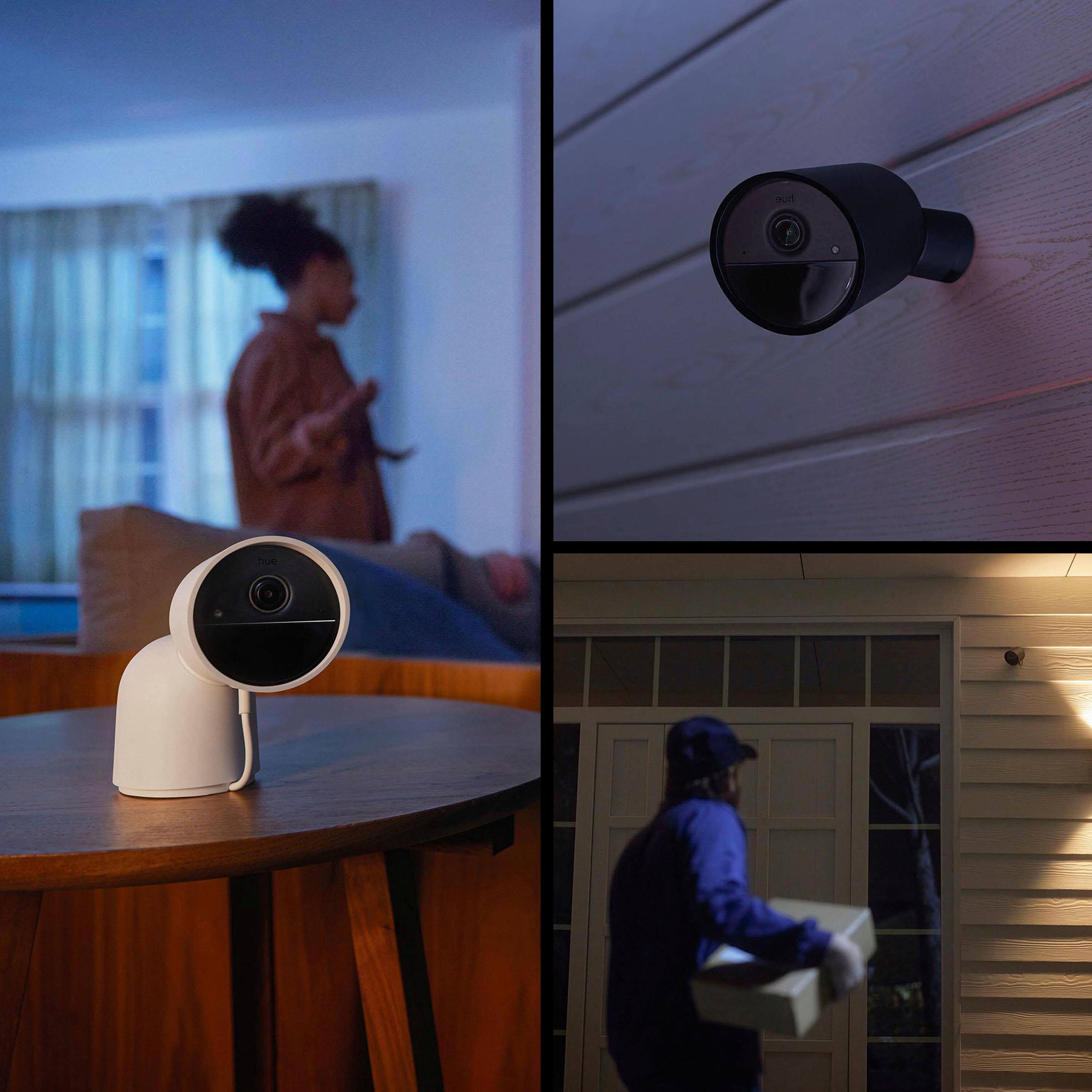 The image features a person holding a box, a man wearing a baseball cap, and a woman standing in a room. There is also a camera on the wall, a couch, and a chair in the scene. The largest text in the image is "hue hue."