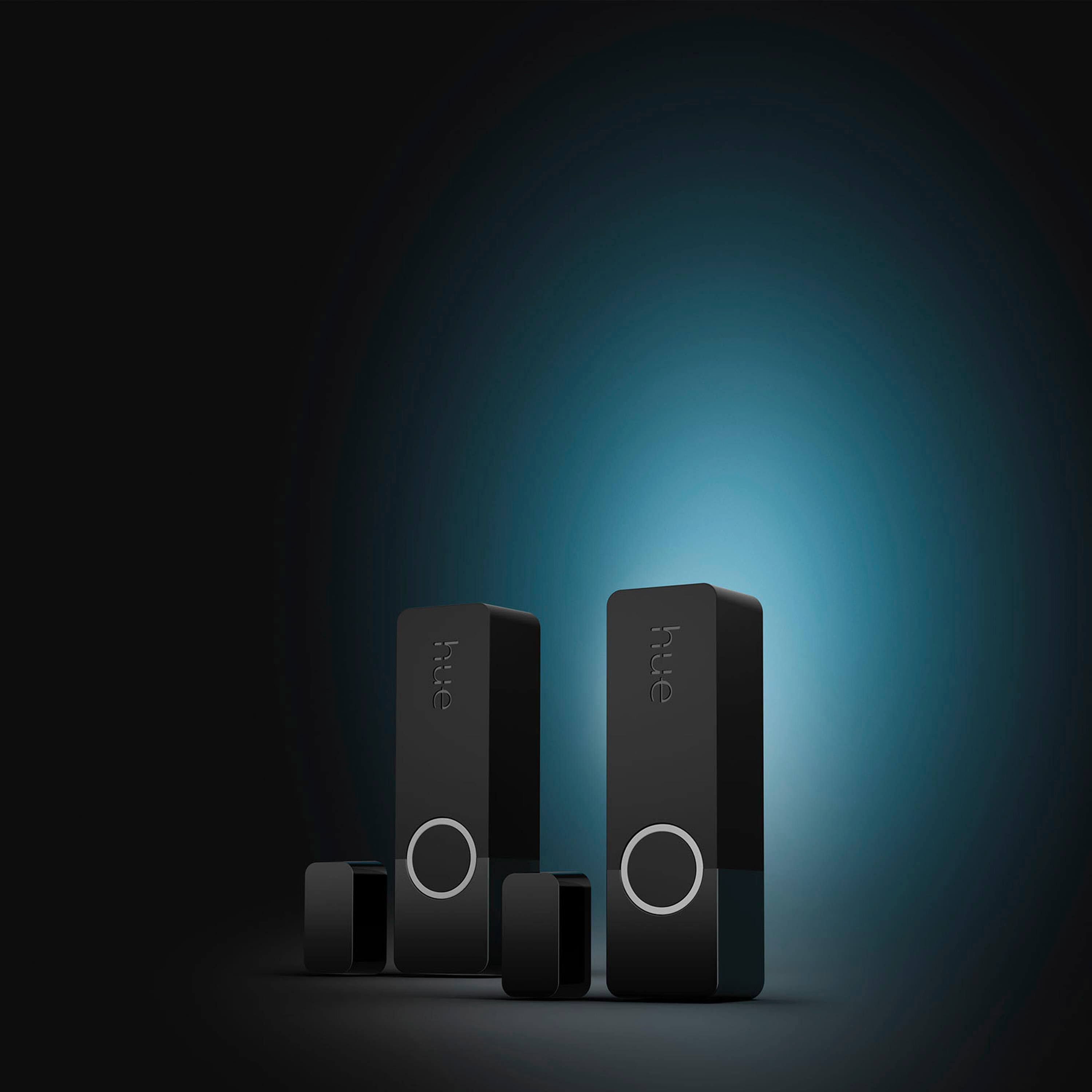 The image features two black speaker boxes with a blue background. The speakers have a circular button on the front, and they are placed next to each other. The blue background creates a contrasting effect with the black speakers, making them stand out in the image.