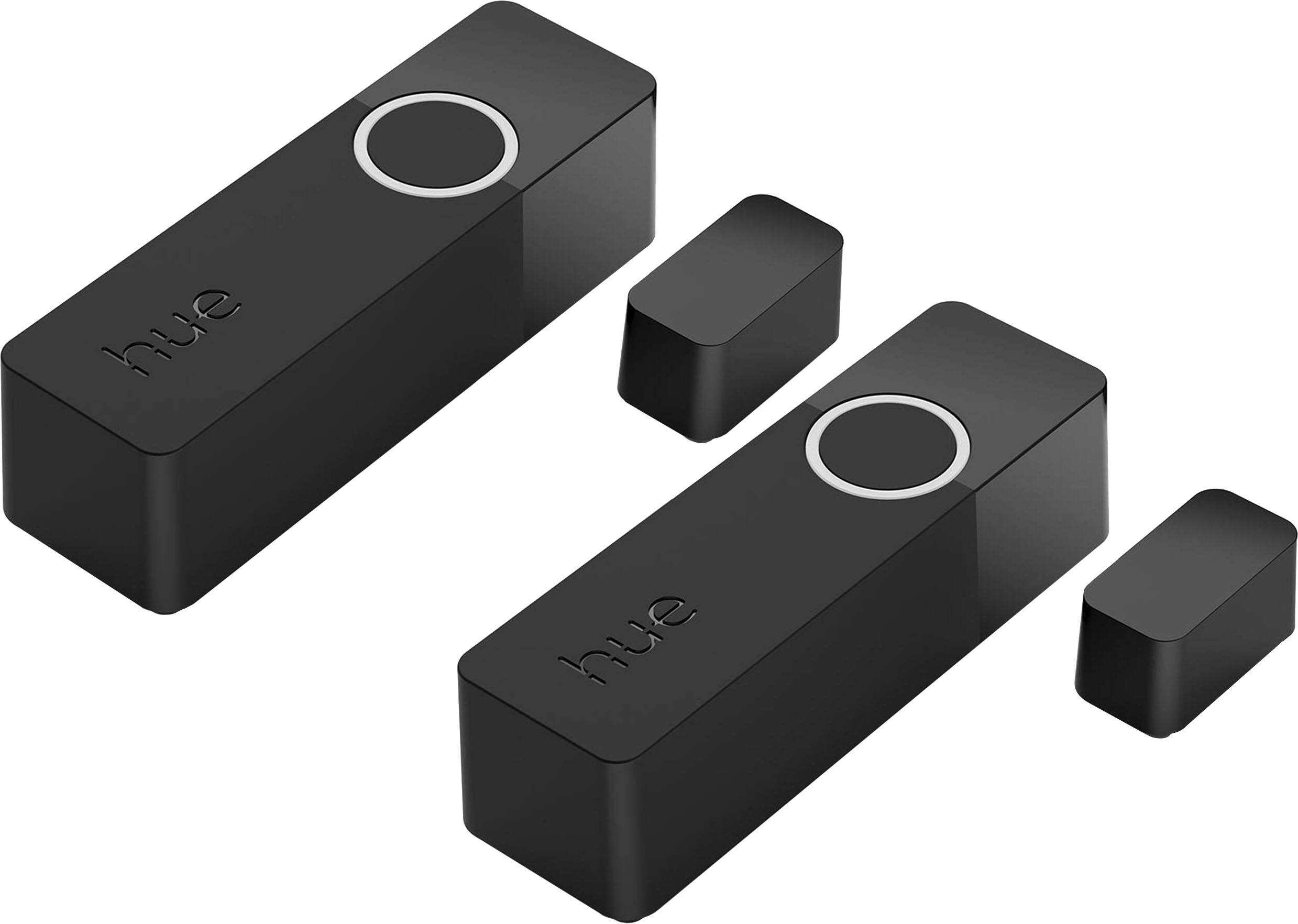 The image features two black Hue remotes and a small black Hue sensor. The remotes are placed next to each other, with one slightly larger than the other. The sensor is positioned between the two remotes, completing the Hue system setup.
