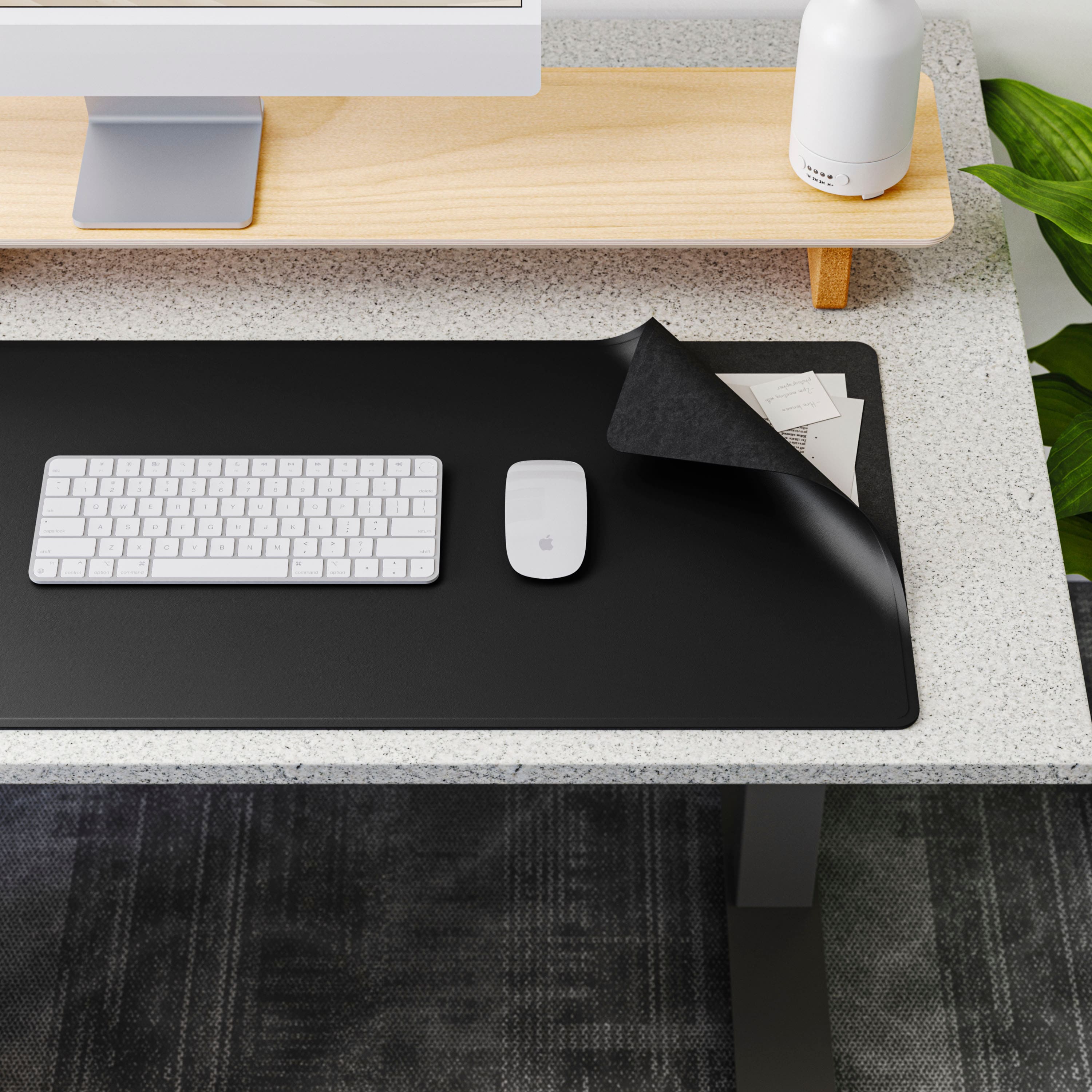 The image features a computer desk with a keyboard, mouse, and monitor. The keyboard is placed on a black mouse pad, and there is a cloth on the desk. A potted plant is also present in the scene, adding a touch of greenery to the space.